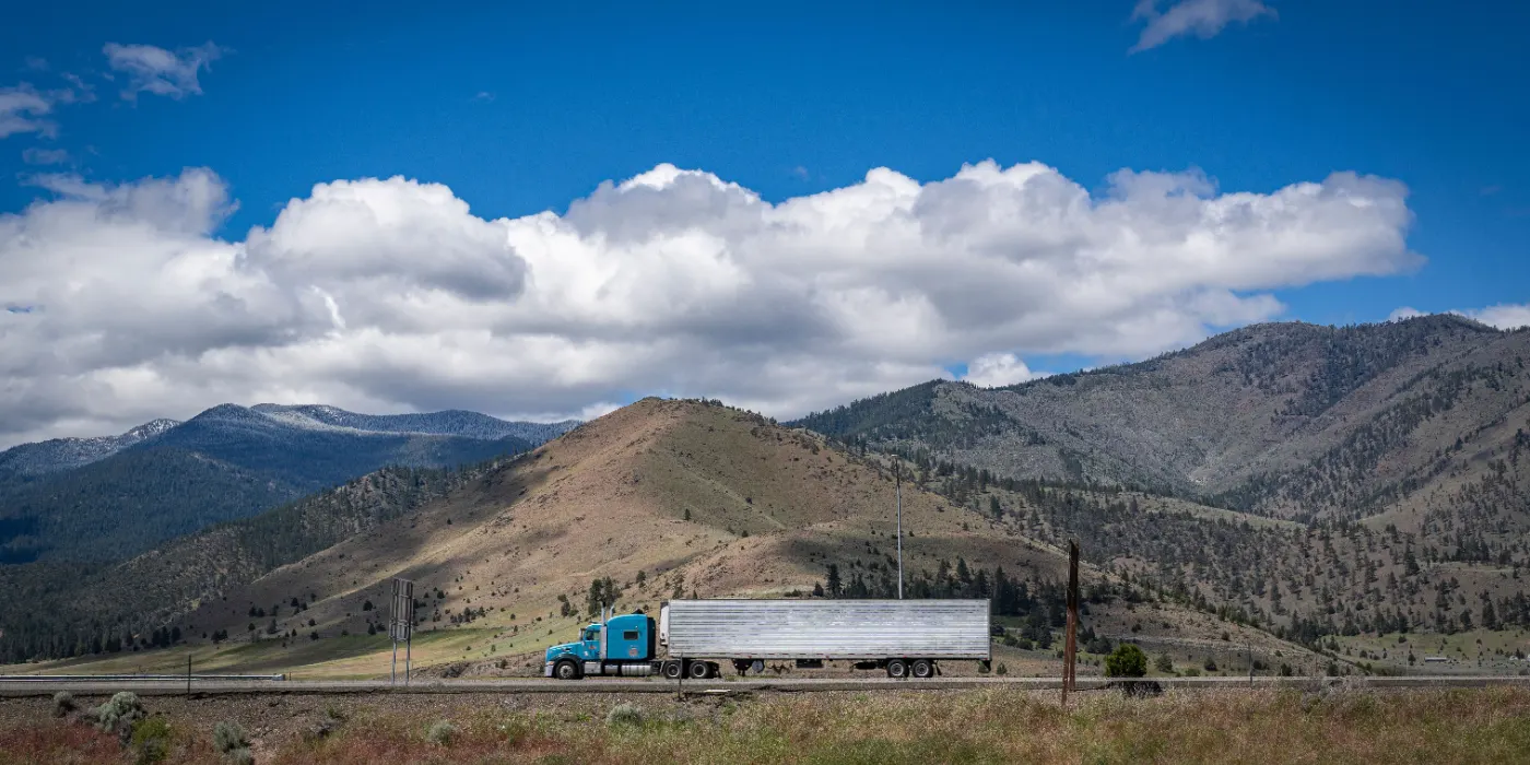 Blue semi tractor pulling a refrigerated trailer on a mountain highway